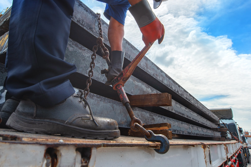 A man working on securing a load on a flatbed edge.